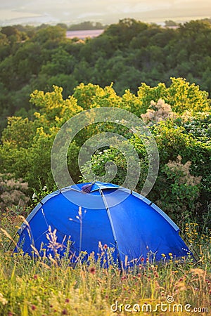 Blue travel tent stands on green glade Stock Photo