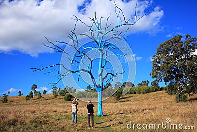 Surrealistic naked blue tree in park with surprised women Stock Photo