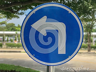 Blue turn left sign on pole Stock Photo