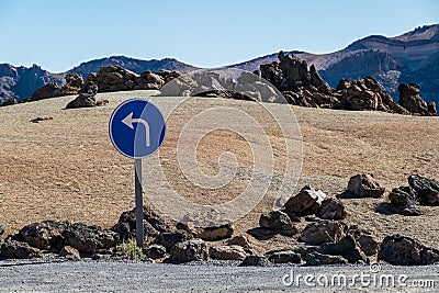 Blue turn left sign on a volcanic desert. Stock Photo