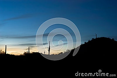 Blue twilight just after sunset glows behind desert hills. Stock Photo