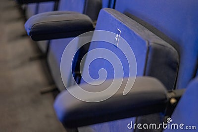 blue velvet chair in concert hall with seat number 4 Stock Photo