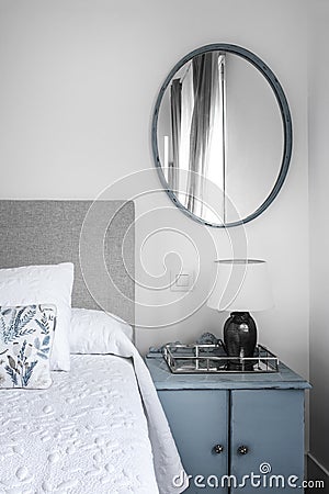 Blue vintage side table and gray fabric upholstered bedroom headboard Stock Photo