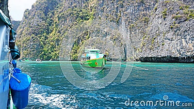 Blue water, green hills and steep rocks. The boat sails near the island. Boat with tourists in the Bay Editorial Stock Photo