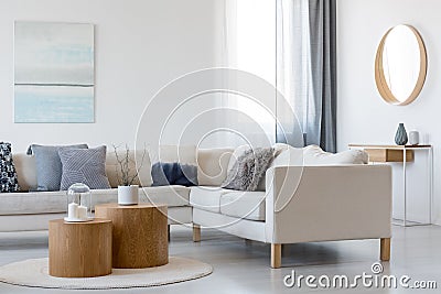 Blue and white painting and mirror in wooden frame in elegant living room interior with corner sofa and coffee table Stock Photo