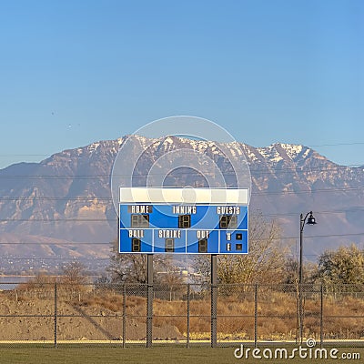 Blue and white baseball scoreboard above the chain link fence at a sports field Stock Photo