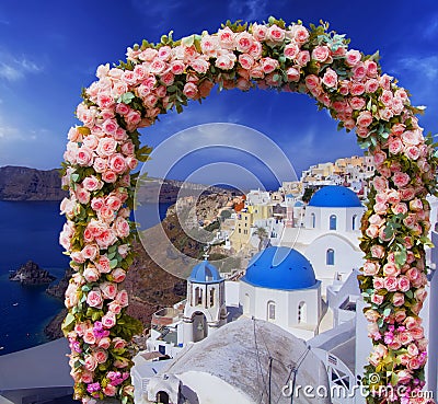 Wedding at Santorini. Beautiful arch decorated with flowers of roses with blue church of Oia, Santorini, Greece at most romantic Stock Photo