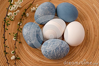 Easter eggs and flowers on a wooden plate, view from above Stock Photo