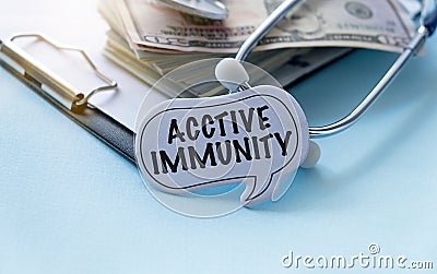 On a blue-white surface lies a stethoscope and a notepad with the inscription - Active Immunity Stock Photo