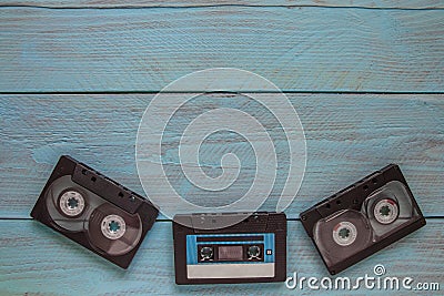 On a blue wooden background at the bottom of the frame are three audio cassettes. There is a place for the text on the top Stock Photo