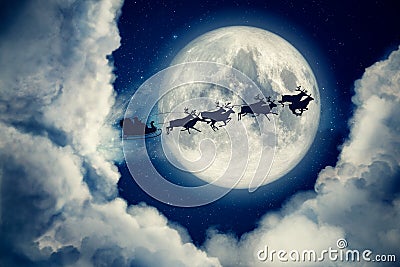 Blue xmas eve night with moon and clouds with Santa Claus sleight and reindeer silhouette flying to bring gifts and Stock Photo