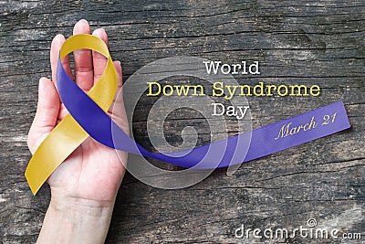 Blue yellow awareness ribbon on helping hand for World down syndrome day WDSD March 21 raising support on patient Stock Photo