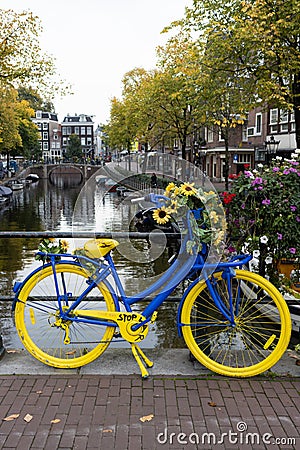 Blue and Yellow Bike Supporting Ukraine on a Bridge above a Canal during Autumn in Amsterdam Editorial Stock Photo