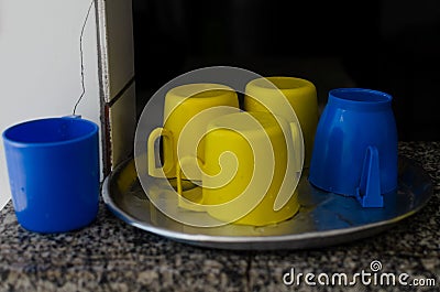 blue and yellow colored plastic cups on top of a metal tray Stock Photo