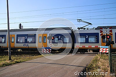 Blue yellow white sprinter train at a railroad crossing in Moordrecht Editorial Stock Photo