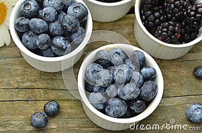 Blueberries and blackberries garden daisies on rustic wood table Stock Photo