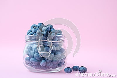 Blueberries in a glass bowl on a pink background, a berry in a glass jug. Vegetarian food concept Stock Photo