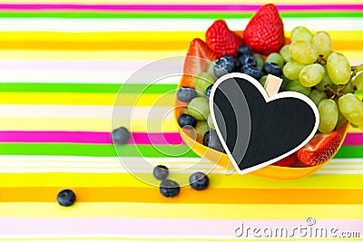 Blueberries, grapes and strawberries in a bowl on a striped table, black heart Stock Photo