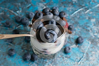 Blueberries in a teaspoon close-up and fancy delicious dessert with chocolate, yogurt and raspberry in a glass cup on a Stock Photo