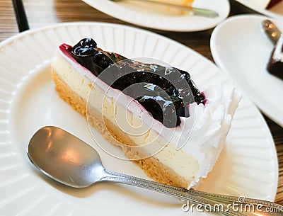 Blueberry Cheese Pie and silver spoon on white porcelain dish Stock Photo