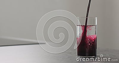 Blueberry juice pour into water in highball glass on kitchen countertop Stock Photo