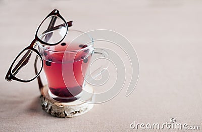 Blueberry tea in a glass cup and with glasses in a brown frame on it, Stock Photo