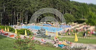 Blur image of people in public swimming pool in forest during summer season Stock Photo