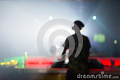 Blurred background : Club, disco DJ playing and mixing music for crowd of happy people. Nightlife, concert lights Stock Photo