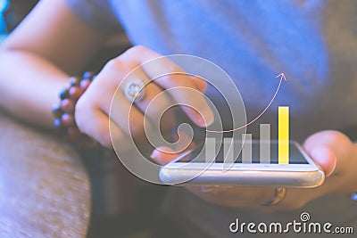 Blurred background of financial planning and investment concept. Young woman holding smartphone with graph and rows. Stock Photo