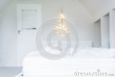 Blurred background of glowing lights Christmas tree on the white wall above the bed in the bedroom. Simple, minimal conscientious Stock Photo