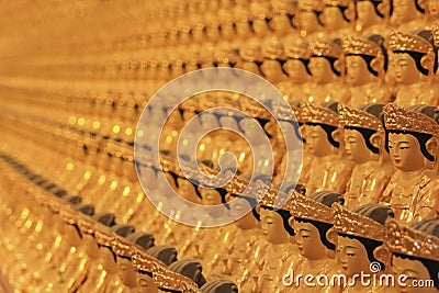 Blurred background image of wall in ancient asian buddhist temple with umpteen small golden Buddha statues. Stock Photo