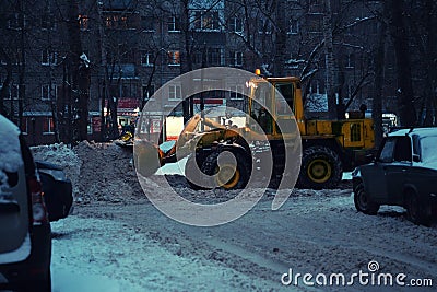 Blurred background. Night city lights blur. Snow removal vehicle removing snow Editorial Stock Photo