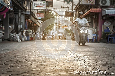 Blurred background - a quiet calm deserted city street in Asia in Thailand at sunset in the evening. passing moped bike Stock Photo