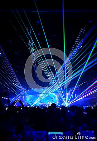 Blurred crowd at concert : Silhouette people crowd happy and cheering in front of colorful stage with bright laser light beam.â€‹ Editorial Stock Photo