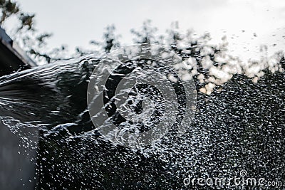 Blurred drops of water escaping from a hose. Watering, irrigation with water. Stock Photo