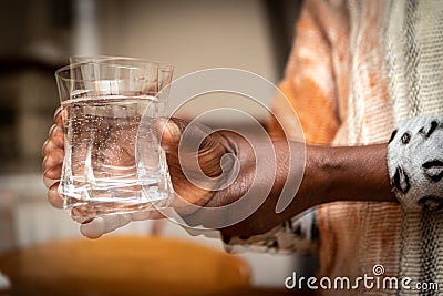 Blurred effect on the hands of a Parkinson`s disease patient with tremors while holding a glass Stock Photo