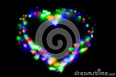 Blurred festive background with defocused colourful glitter formed a heart, bokeh in a shape of a heart. Original photographic Stock Photo