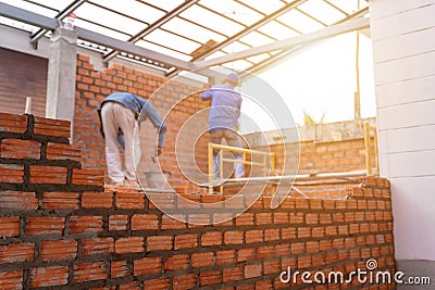 Blurred image of Bricklayer worker installing brick masonry on exterior wall with trowel putty knife on construction site Stock Photo