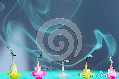 Blurred image of fading candles, blurry smoke, blue background. Holidays, Birthday concept. Small colorful melted candles. Stock Photo