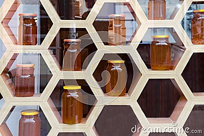 Blurred image, view through the glass of wooden shop window with glass jars with honey. Stock Photo