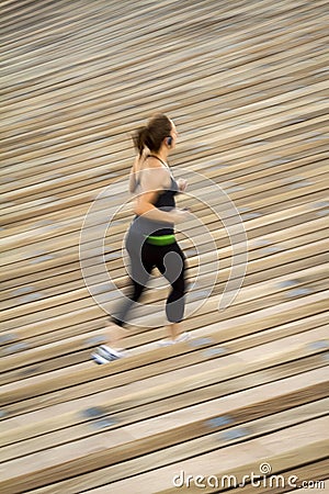 Blurred image of Woman jogging on rows of wood venue seating Editorial Stock Photo