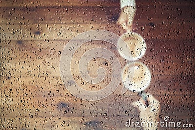 Blurred male`s and female`s hands in the knitted mittens with an cup of coffee under a glass roof with raindrops. Stock Photo