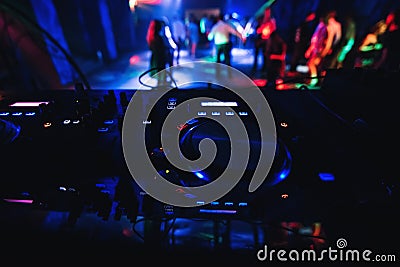 Blurred people dancing on dance floor of nightclub with DJ mixer in front to control the music Stock Photo