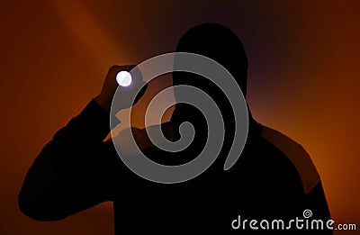 Blurred photo. Burglar in dark clothes holding the flashlight. Dangerous robber in mask with a torch. Criminal man Stock Photo