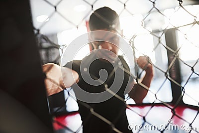 Blurred picture. Strong man is boxing in the gym behind the fence. Haves daily exercise Stock Photo