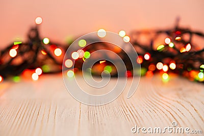 Blurred product background with Christmas New Year colorful light bulbs garland and wooden table. Selective focus, copy space for Stock Photo