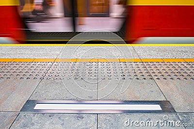 Blurred red subway train in Warsaw Poland, tactile paving for vi Stock Photo