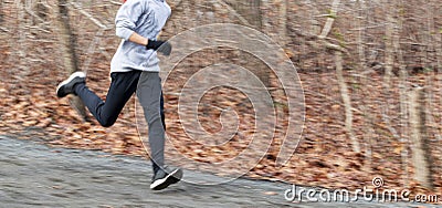 Blurred runner showing speed running downhill on a dirt path in the woods Stock Photo