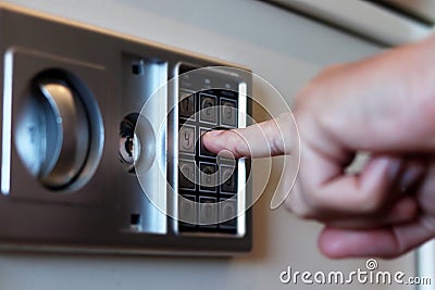 Blurred safe with combination lock and human hand in a hotel room, closeup numbers with tilt shift effect. Selective Stock Photo