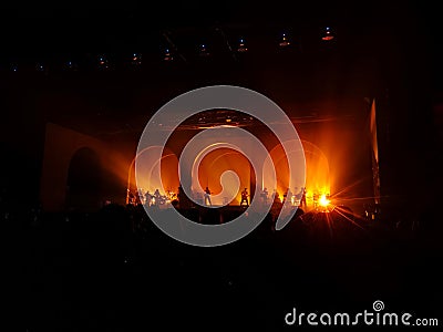 Blurred silhouette music band perform in concert with red laser light beam .Arches and doors with lighting on stage. Stock Photo